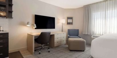 Guest room workspace in Sonesta Simply Suites Irvine East Foothill, furnished with desk, chair, lamp, and television.