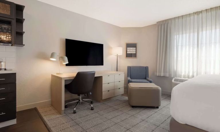 Guest room workspace in Sonesta Simply Suites Irvine East Foothill, furnished with desk, chair, lamp, and television.