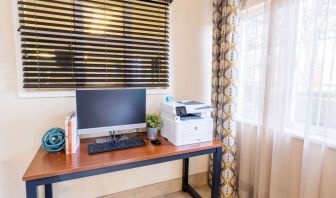 The hotel business center has a printer, monitor, keyboard, mouse, and a nearby window.