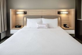 Sonesta Select Nashville Airport Suites deluxe king bed room, featuring bedside lamps and telephone.