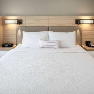 Sonesta Select Nashville Airport Suites deluxe king bed room, featuring bedside lamps and telephone.