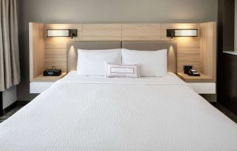 Sonesta Select Nashville Airport Suites deluxe king bed room, featuring bedside lamps and telephone.