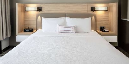 Sonesta Select Nashville Airport Suites deluxe king bed room, featuring bedside lamps and telephone.