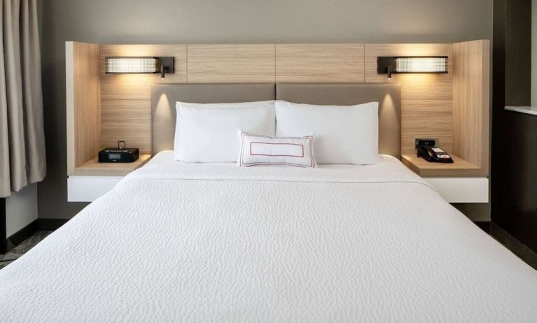 Sonesta Select Nashville Airport Suites deluxe king bed room, featuring bedside lamps and telephone.