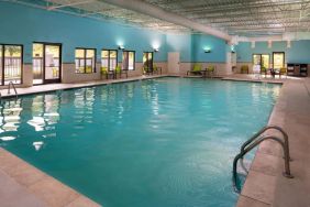 Sonesta Select Nashville Airport Suites’ indoor pool is brightly lit, has chairs by the side, and is adjacent to the patio.