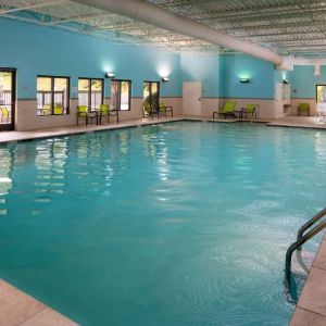 Sonesta Select Nashville Airport Suites’ indoor pool is brightly lit, has chairs by the side, and is adjacent to the patio.