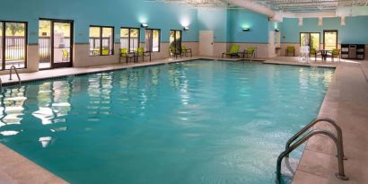 Sonesta Select Nashville Airport Suites’ indoor pool is brightly lit, has chairs by the side, and is adjacent to the patio.