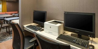 The hotel business center includes a pair of computer workstations and a printer.