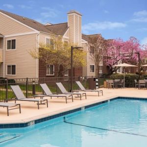 Shaded tables and chairs, as well as sun loungers, are by the side of Sonesta ES Suites Nashville Brentwood’s outdoor pool.