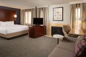 Sonesta ES Suites Nashville Brentwood king bed guest room, furnished with sofa, desk, and TV.