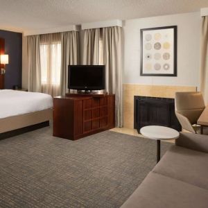 Sonesta ES Suites Nashville Brentwood king bed guest room, furnished with sofa, desk, and TV.