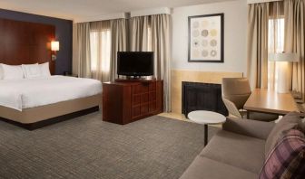 Sonesta ES Suites Nashville Brentwood king bed guest room, furnished with sofa, desk, and TV.