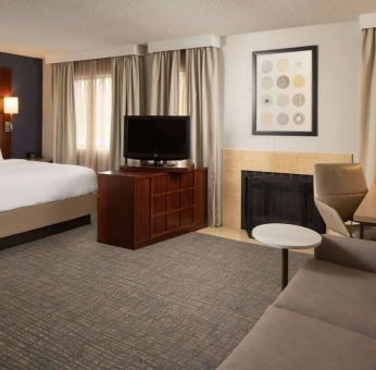 Sonesta ES Suites Nashville Brentwood king bed guest room, furnished with sofa, desk, and TV.