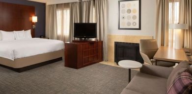 Sonesta ES Suites Nashville Brentwood king bed guest room, furnished with sofa, desk, and TV.