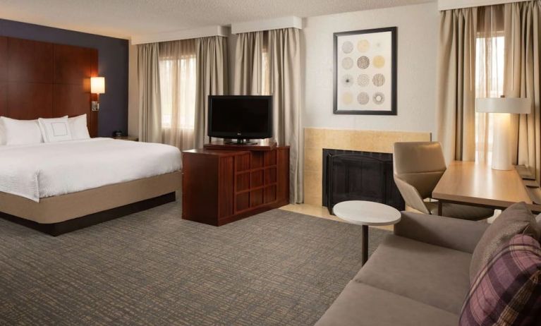 Sonesta ES Suites Nashville Brentwood king bed guest room, furnished with sofa, desk, and TV.