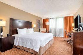 Double bed guest room in Sonesta Miami Airport, including armchair, TV, and window.