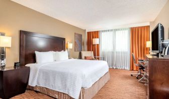 Double bed guest room in Sonesta Miami Airport, including armchair, TV, and window.