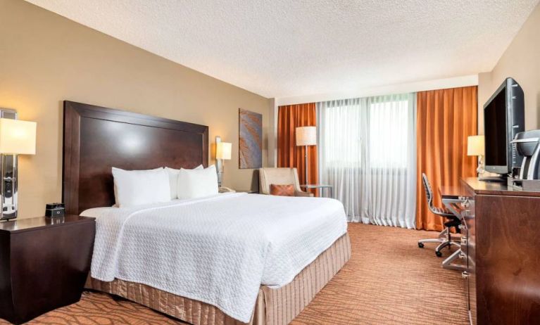 Double bed guest room in Sonesta Miami Airport, including armchair, TV, and window.