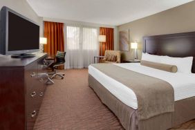 Sonesta Miami Airport double bed guest room, furnished with television, armchair, and workspace desk and chair.