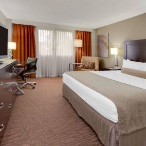 Sonesta Miami Airport double bed guest room, furnished with television, armchair, and workspace desk and chair.