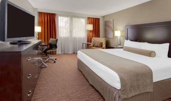 Sonesta Miami Airport double bed guest room, furnished with television, armchair, and workspace desk and chair.