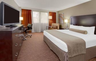 Sonesta Miami Airport double bed guest room, furnished with television, armchair, and workspace desk and chair.