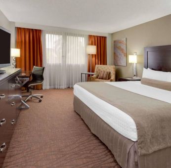 Sonesta Miami Airport double bed guest room, furnished with television, armchair, and workspace desk and chair.