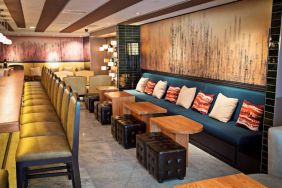 The hotel bar has a mix of traditional tall stools and table seating, and a hard floor.