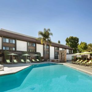 The outdoor pool of Sonesta Silicon Valley has nearby sun loungers, tables and chairs, and plenty of shade available.