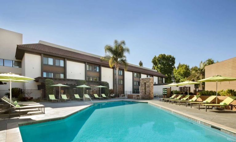 The outdoor pool of Sonesta Silicon Valley has nearby sun loungers, tables and chairs, and plenty of shade available.