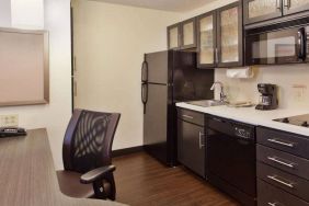 Sonesta Simply Suites Cleveland North Olmsted Airport guest room workspace desk and chair, and adjacent kitchenette.