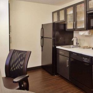 Sonesta Simply Suites Cleveland North Olmsted Airport guest room workspace desk and chair, and adjacent kitchenette.