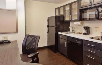 Sonesta Simply Suites Cleveland North Olmsted Airport guest room workspace desk and chair, and adjacent kitchenette.