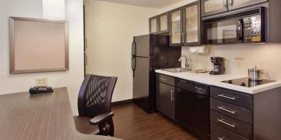 Sonesta Simply Suites Cleveland North Olmsted Airport guest room workspace desk and chair, and adjacent kitchenette.