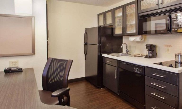 Sonesta Simply Suites Cleveland North Olmsted Airport guest room workspace desk and chair, and adjacent kitchenette.