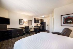 Double bed guest room in Sonesta Simply Suites Cleveland North Olmsted Airport, including workspace desk and chair, plus kitchenette.