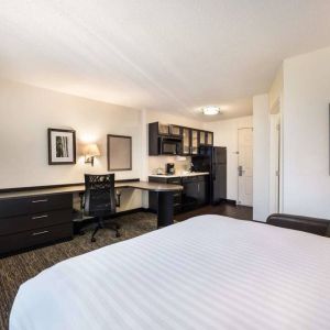 Double bed guest room in Sonesta Simply Suites Cleveland North Olmsted Airport, including workspace desk and chair, plus kitchenette.