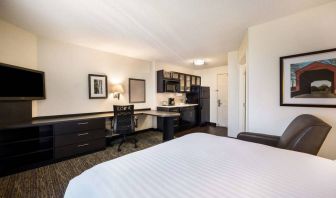 Double bed guest room in Sonesta Simply Suites Cleveland North Olmsted Airport, including workspace desk and chair, plus kitchenette.