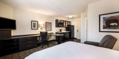 Double bed guest room in Sonesta Simply Suites Cleveland North Olmsted Airport, including workspace desk and chair, plus kitchenette.