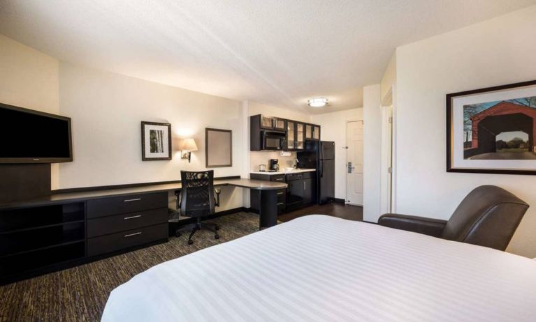 Double bed guest room in Sonesta Simply Suites Cleveland North Olmsted Airport, including workspace desk and chair, plus kitchenette.