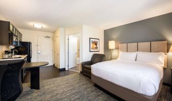 Sonesta Simply Suites Cleveland North Olmsted Airport double bed guest room, featuring armchair, desk, and kitchenette.