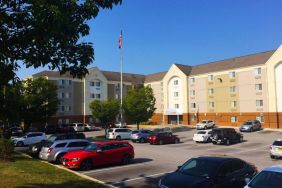 The hotel exterior features ample parking, pleasant greenery, and a fluttering Stars and Stripes flag.