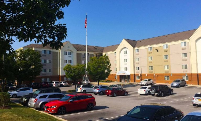 The hotel exterior features ample parking, pleasant greenery, and a fluttering Stars and Stripes flag.