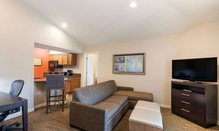 Sonesta ES Suites Dulles Airport guest room lounge, furnished with sofa, chairs, desk, and TV.