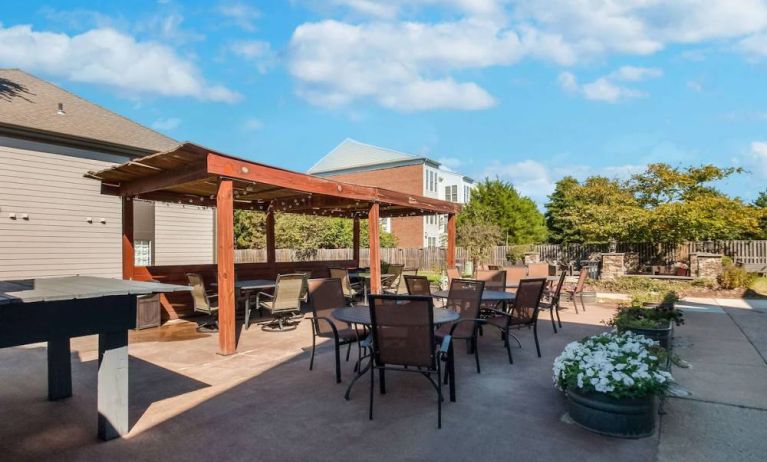 Sonesta ES Suites Dulles Airport’s terrace features tables and chairs, some under cover, and potted plants.