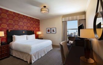 The Stephen F Austin Royal Sonesta Hotel double bed guest room, including window and workspace desk and chair.