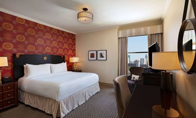 The Stephen F Austin Royal Sonesta Hotel double bed guest room, including window and workspace desk and chair.