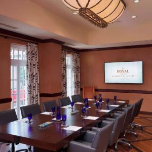 The Stephen F Austin Royal Sonesta Hotel meeting room, with long wooden table, ten swivel chairs, and wall-mounted television.