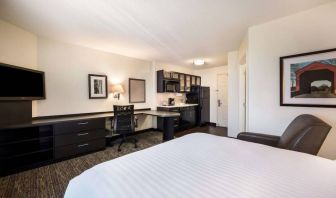 Double bed guest room in Sonesta Simply Suites Arlington, featuring workspace desk and chair, plus TV and kitchenette. 