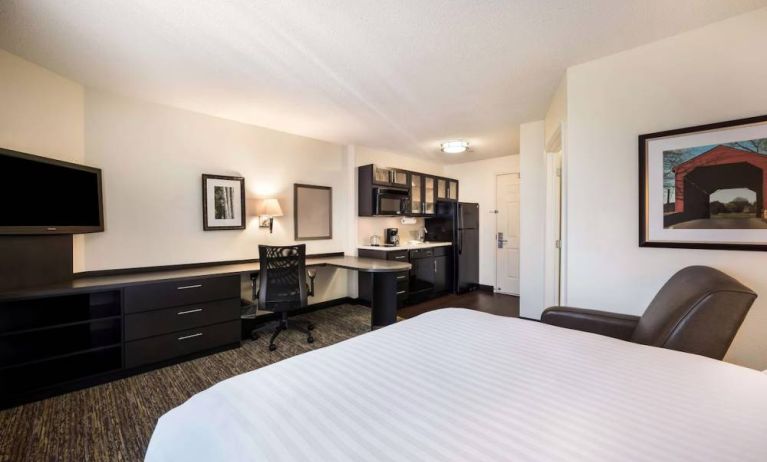 Double bed guest room in Sonesta Simply Suites Arlington, featuring workspace desk and chair, plus TV and kitchenette. 